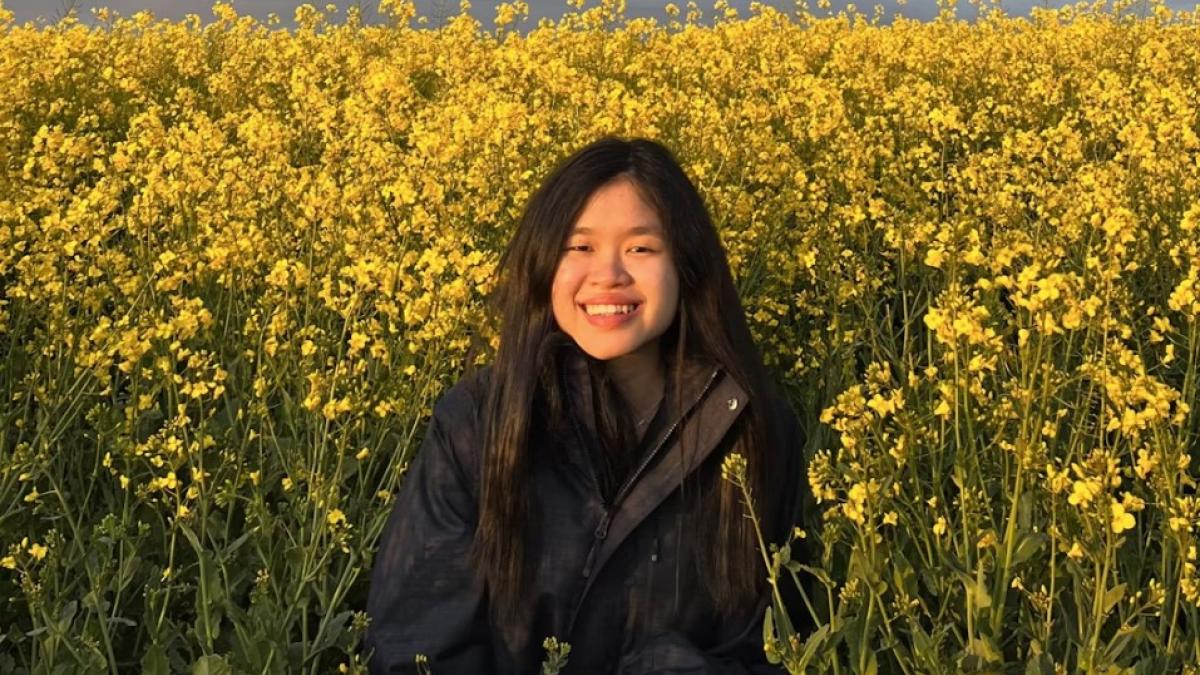 A photograph of Phei, a Year 4 Medical student, smiling in a field of yellow flowers.