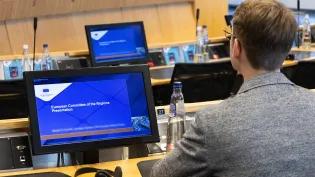 A man looks at a screen that displays the text 'European Committee of the Regions'