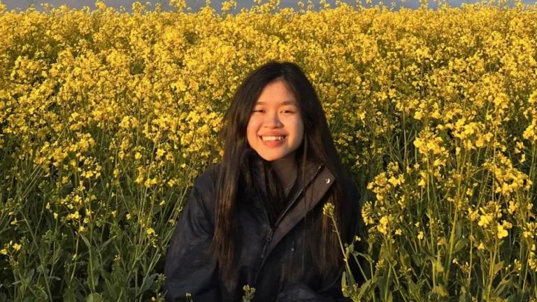 A photograph of Phei, a Year 4 Medical student, smiling in a field of yellow flowers.
