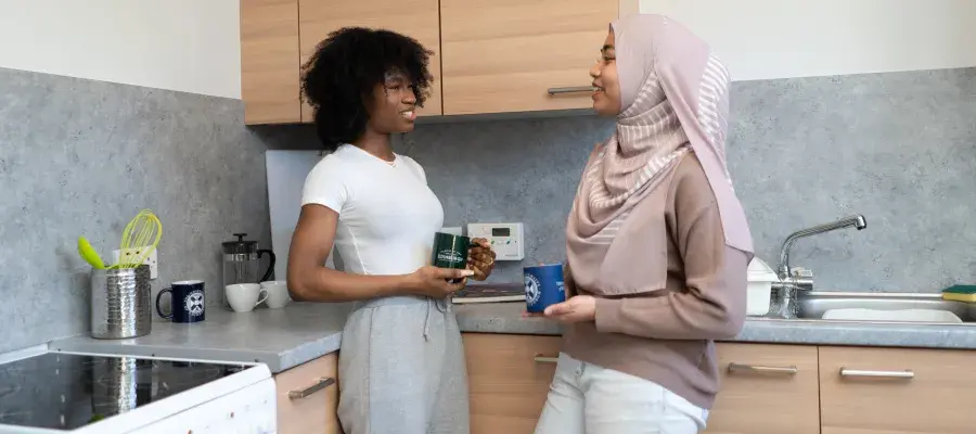 Two students talk in the kitchen of their university accommodation.