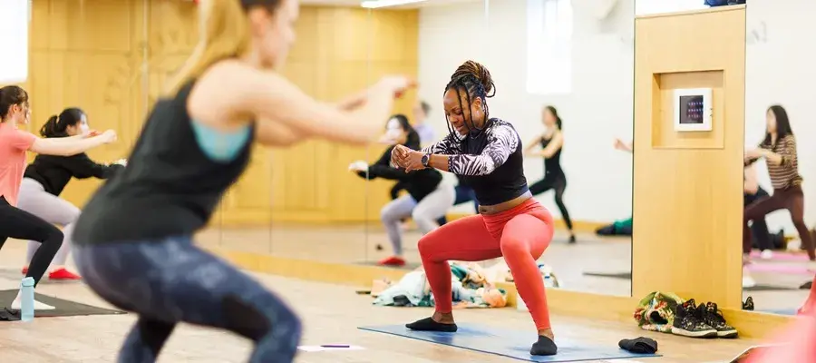 Instructor squatting leading body balance class.