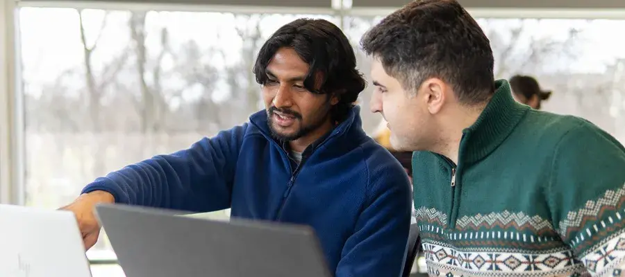 Students chatting while looking at laptops.