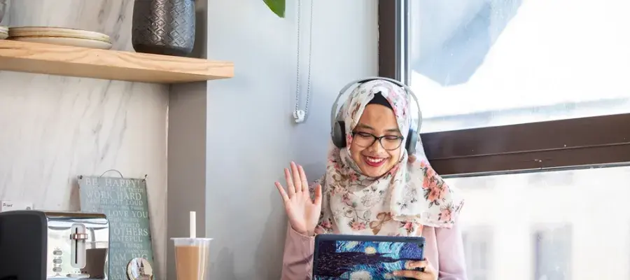 A student waving at an iPad while on a call.