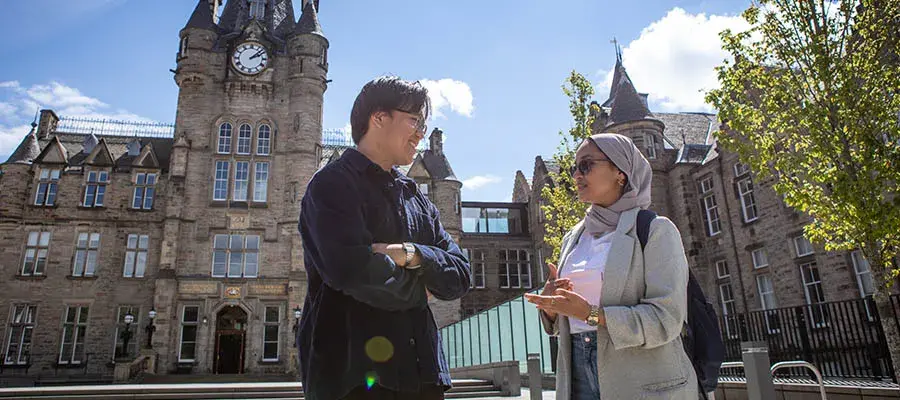 Two students standing chatting outside the Edinburgh Futures Institute building.