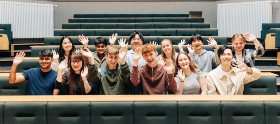 Students sitting in a lecture theatre and waving