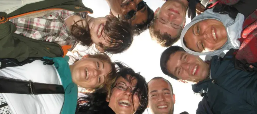 Close-up of faces of eight students huddled together in a circle.