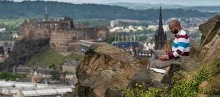 Student with laptop on Arthur's Seat.