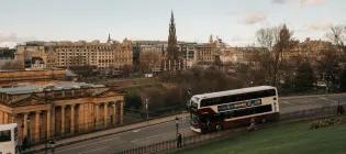 A bus riding down the Mound with the National Gallery and Walter Scott Monument behind it.