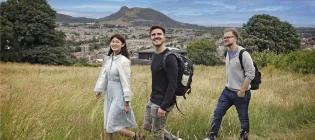Students walking through a field with Arthur's Seat behind them.