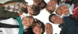 Close-up of faces of eight students huddled together in a circle.