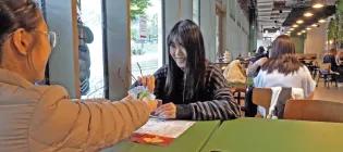 Two students playing cards sitting at a table on campus.