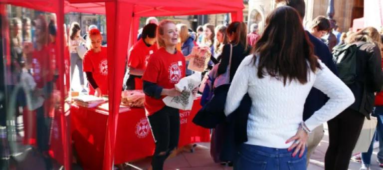 A student ambassador hands out tote bags at a University Open Day.