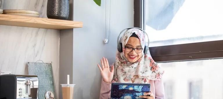 A student waving at an iPad while on a call.