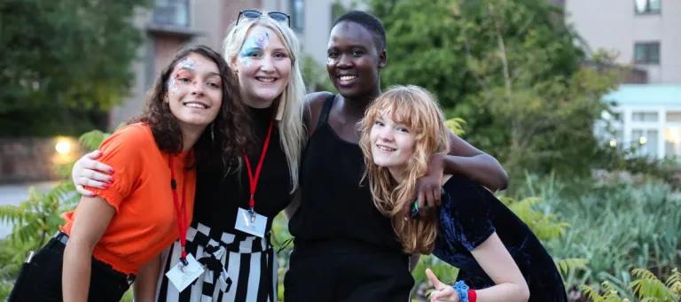 Four students holding each other's shoulders and smiling.