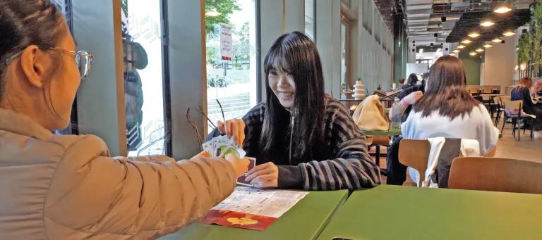 Two students playing cards sitting at a table on campus.