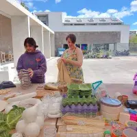 A colourful collection of objects are gathered on a table and a couple of people are picking up objects to play with them.