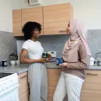 Two students talk in the kitchen of their university accommodation.