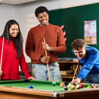 A photo of three students smiling while playing pool at Buccleuch Place Lane common room