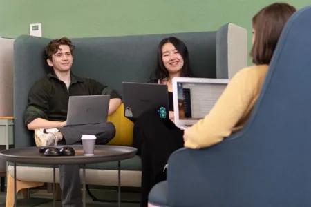 Students sitting on a sofa with laptops.