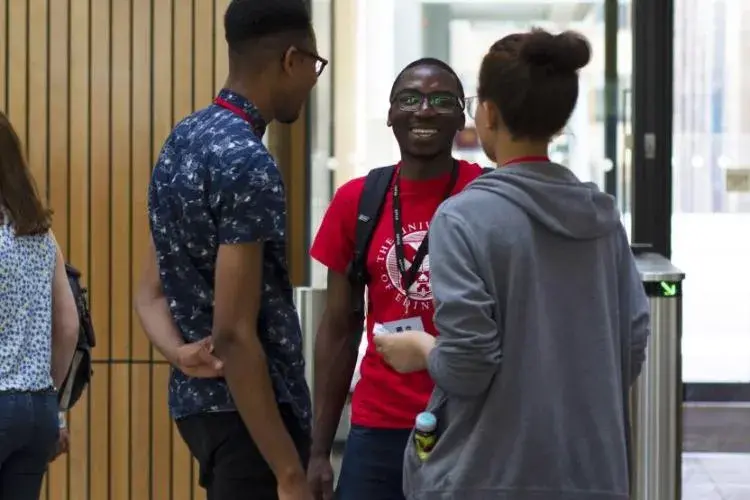 Three students are standing at the entrance to the Main Library and talking.