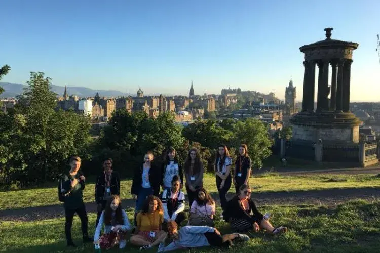 A group of participants is positioned for a photo on Calton Hill. A view on Edinburgh provides the background.