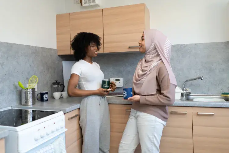 Two students talk in the kitchen of their university accommodation.