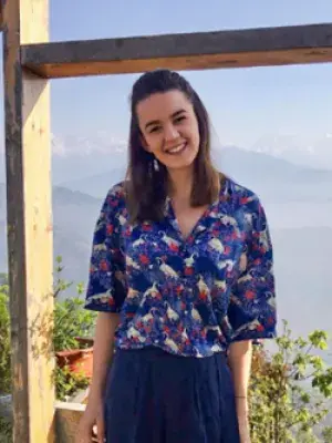 Rosa smiles for the camera in front of a mountainous landscape