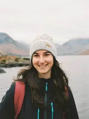 Gail smiles for the camera while standing in front of a river and mountains