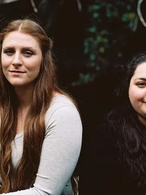 headshot of two women, ana is situated on the right wearing a blue tshirt
