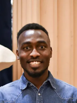 headshot of chigozie smiling at the camera wearing a denim shirt