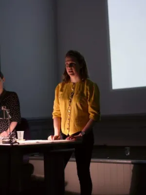 Woman in yellow top delivering a lecture