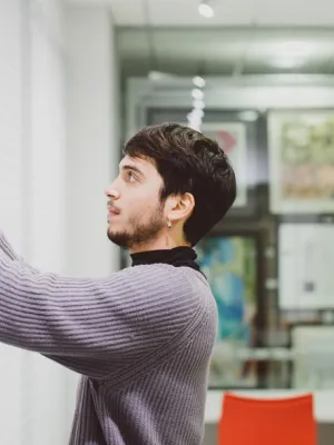 Image shows Diego curating an exhibition, hanging work on the wall
