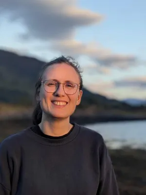 Headshot of woman wearing glasses against a hillside background