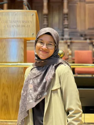 Student smiling at the camera in a University of Edinburgh lecture theatre.