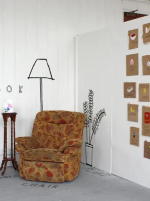 Image shows Sarah's exhibition - featuring a chair, her book and a series of images painted on the wall